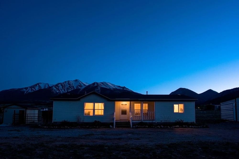 A managed mountain home lit at dusk in the Arkansas River valley near Buena Vista, Colorado